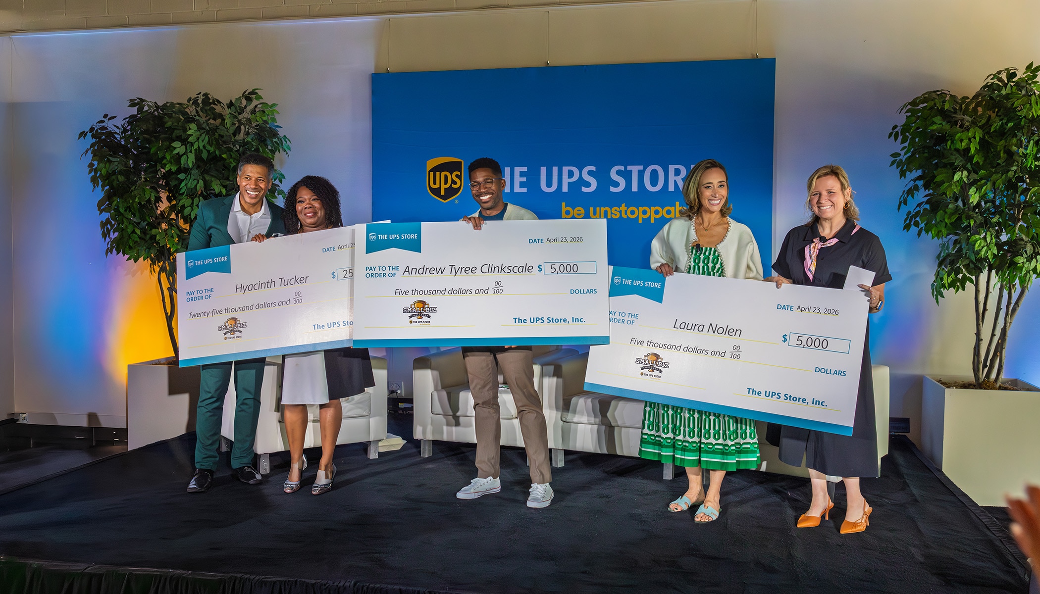 People on stage holding giant checks