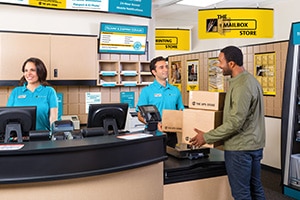 Smiling associates in uniform standing inside The UPS Store
