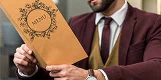Man holding a printed single-use restaurant menu