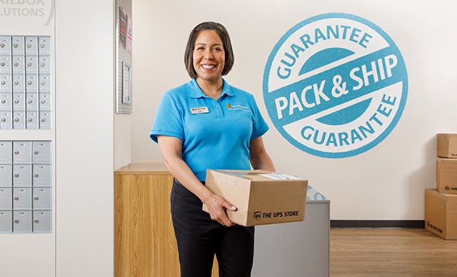 El empleado de The UPS Store sosteniendo un paquete frente a los buzones 